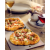 Zwei kleine Pizzen auf einem Brett, Gläser mit Rot- und Weißwein, gestapelte Teller, Topfpflanze auf Holztisch