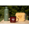 Grüne Thermosflasche, roter Emaille-Becher mit Aufschrift 'camp life' und Holzbox mit 'camp life'-Logo auf einem Holztisch vor unscharfem Waldhintergrund