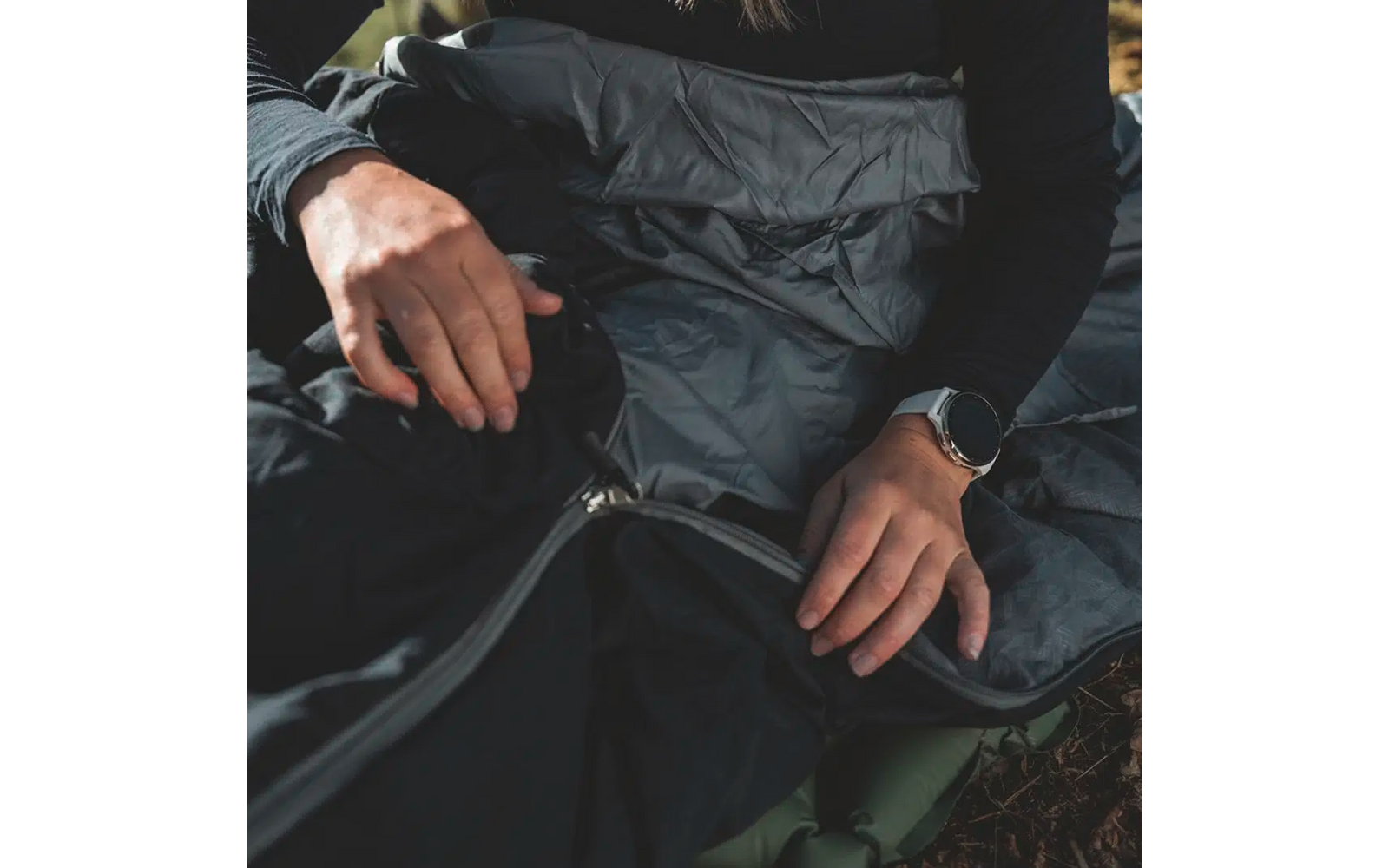 Hände in Wollhandschuhen öffnen den Reißverschluss einer schwarzen Jacke