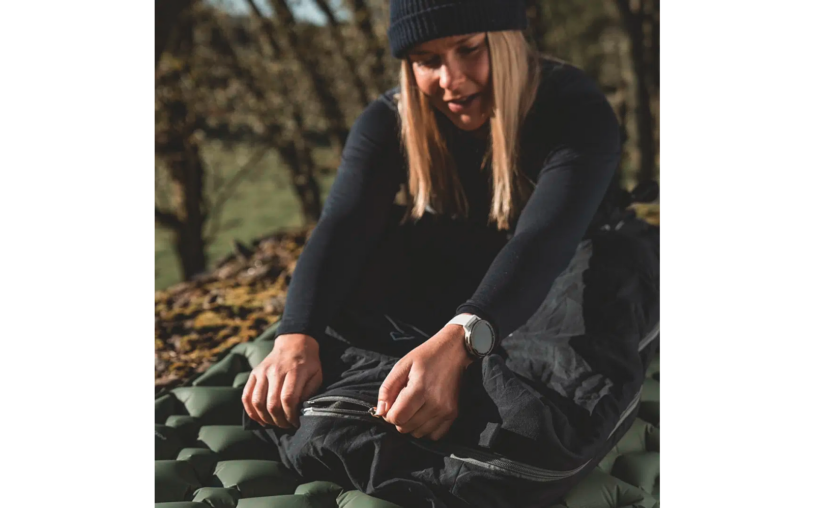 Frau sitzt draußen auf dem Boden und bindet ihre Schuhe