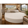 Interieur met rond bed, wit beddengoed, drie kussens, houten kasten, twee ramen met uitzicht op bergen en bos, planten
