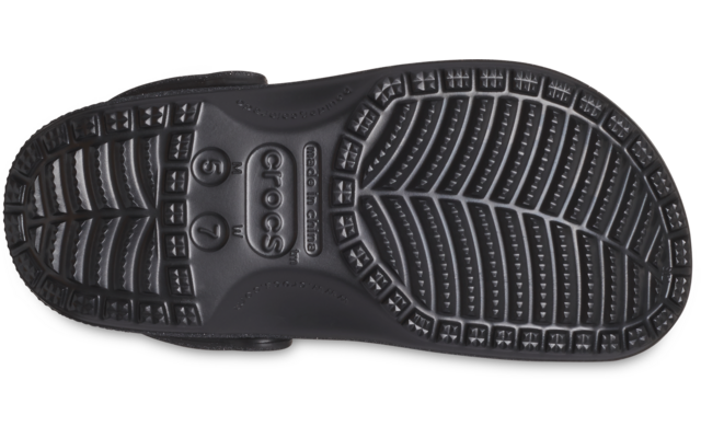 Suela negra de un zueco vista desde abajo, con dibujo del perfil y una correa lateral