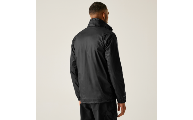 Person von hinten, trägt schwarze Jacke und schwarze Hose, heller einfarbiger Hintergrund