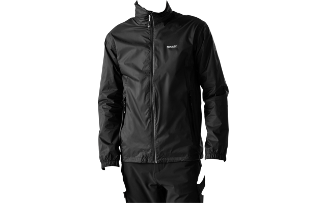 Un uomo indossa una giacca nera con cerniera, un piccolo logo sul petto e due tasche laterali, e pantaloni neri; è in piedi davanti a uno sfondo chiaro, guarda verso destra con le mani lungo i fianchi