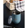 Blauwe thermosbeker met deksel op zwarte tafel, witte krat en blauw-wit geruit doek op de achtergrond