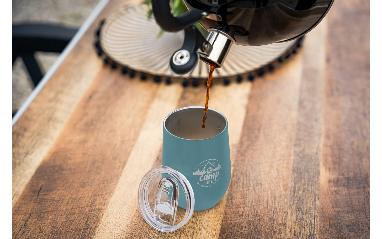Koffiepot die koffie giet in een blauwe beker op een houten tafel