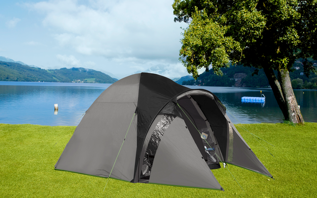 Gray tent on green grass with lake and mountains in the background