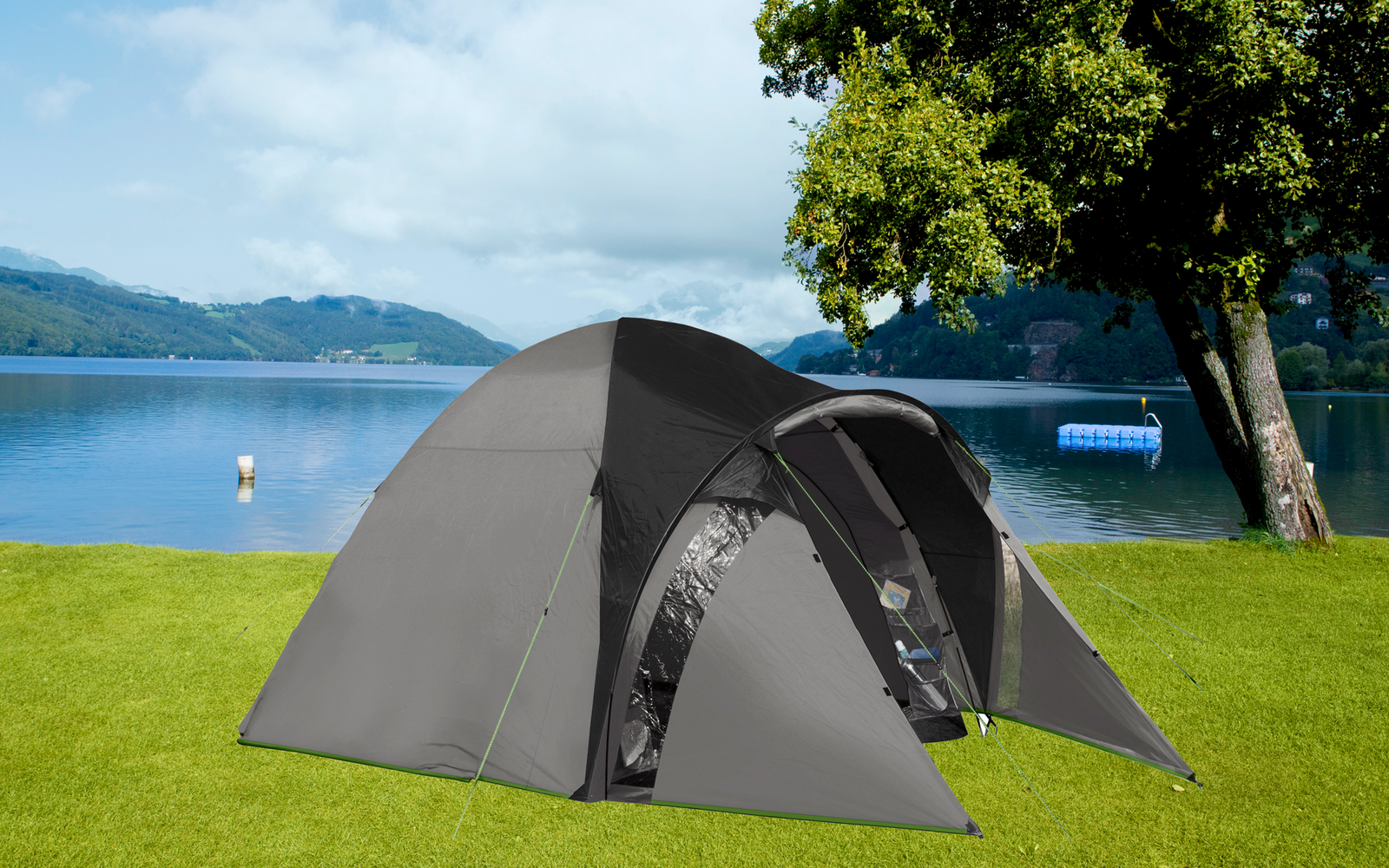 Gray tent on green grass with lake and mountains in the background
