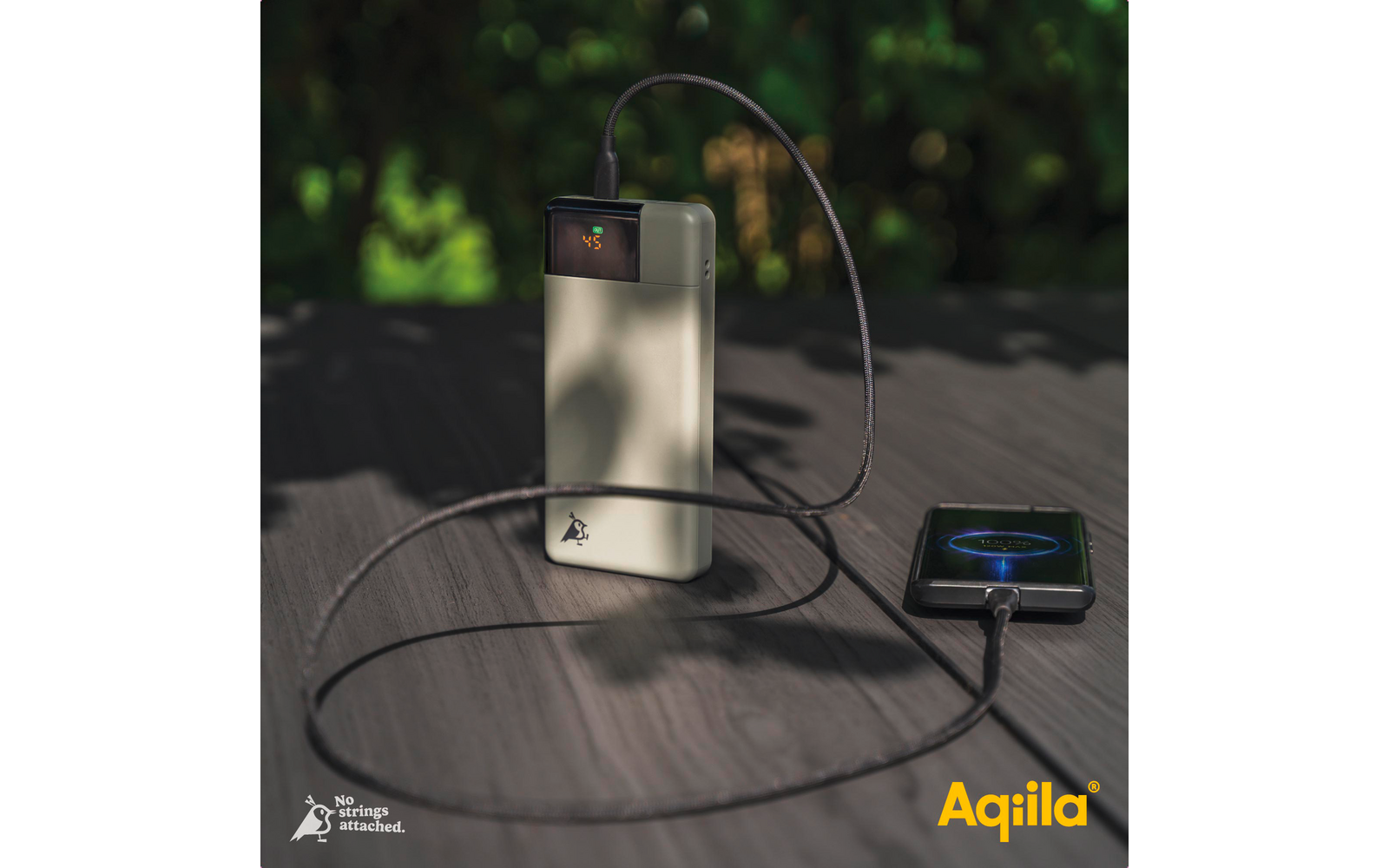 Smartphone et chargeur avec câble sur une table ronde en bois à l'extérieur
