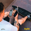 Un homme avec des tatouages tenant deux smartphones dans ses mains, assis sur un sol en carreaux rouges
