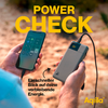 Main tenant un smartphone avec une application ouverte, à côté d'une batterie externe noire avec câble sur un sol sablonneux