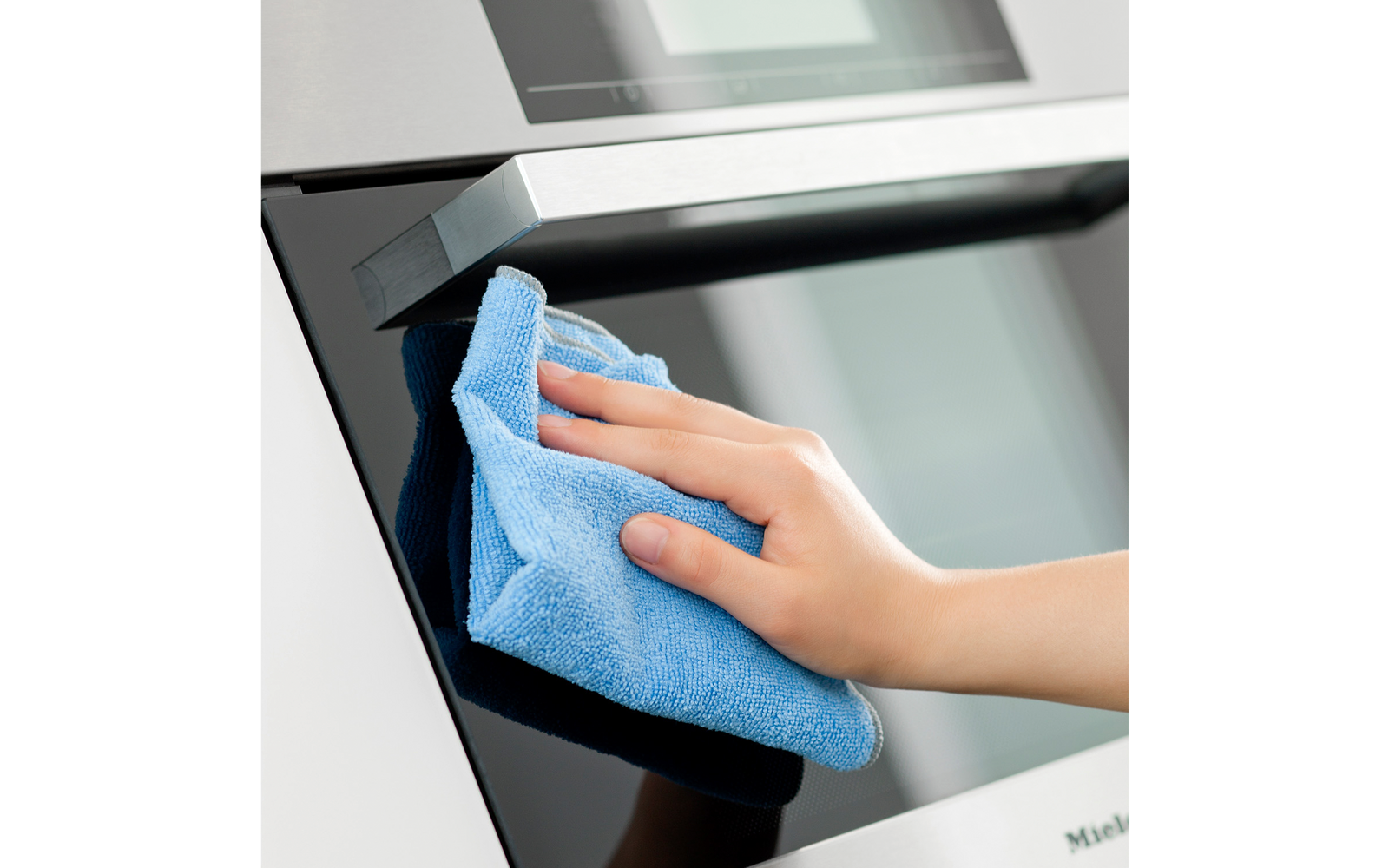 Hand mit blauem Tuch an der Griffstange und Glastür eines Backofens