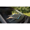Tablet liegt auf der Motorhaube eines Autos, umgeben von Bäumen im Hintergrund