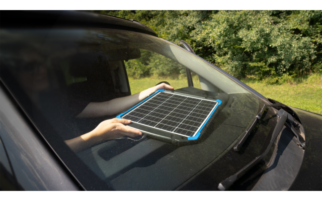 Tablet liegt auf der Motorhaube eines Autos, umgeben von Bäumen im Hintergrund