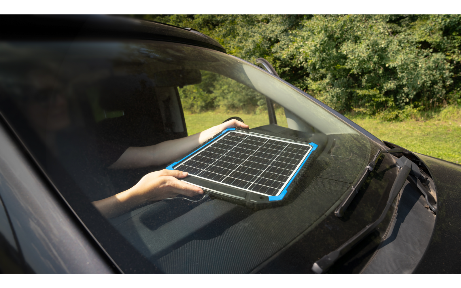 Tablet liegt auf der Motorhaube eines Autos, umgeben von Bäumen im Hintergrund