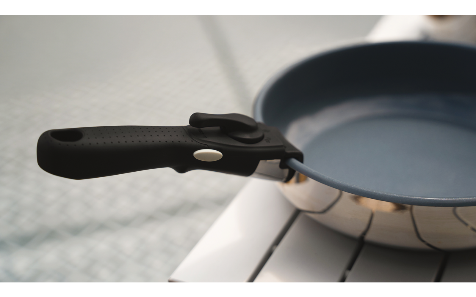 Eine schwarze Bratpfanne mit Holzgriff liegt auf einem weißen Untergrund