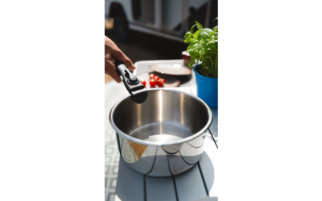 Eine Hand hält eine schwarze Pinzette und legt eine Erdbeere in eine Metallschüssel