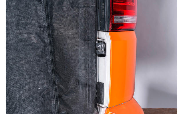 Nahaufnahme eines Rücklichts an einem orangefarbenen Fahrzeug, rechts neben einem schwarzen Stoffdach