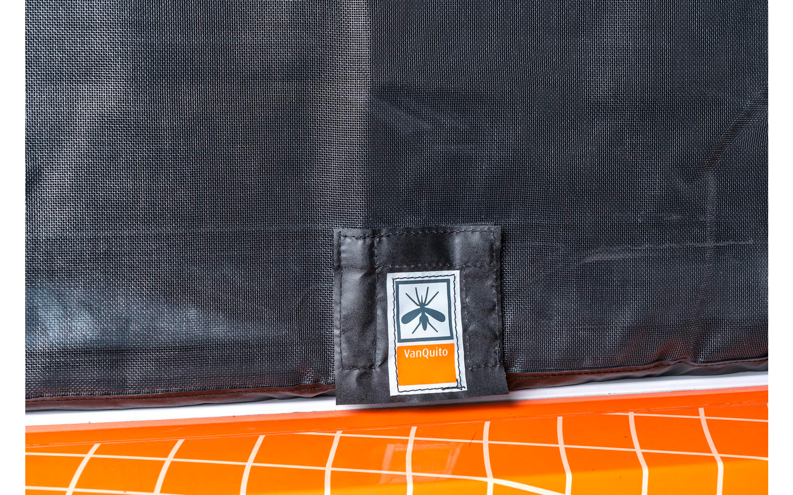 Nahaufnahme eines orangefarbenen Kunststoffgitters mit schwarzer Abdeckung und einem kleinen weißen Etikett