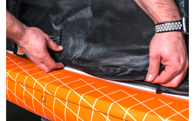 Hände rollen einen orangen Teppich mit weißen Linien aus