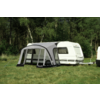 Caravan with attached awning on a grassy area in front of trees