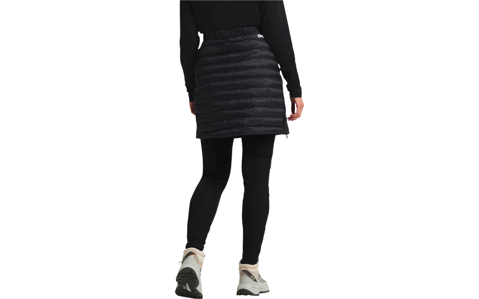 Person von hinten mit schwarzer gesteppter Jacke, schwarzem Rock und weißen Turnschuhen