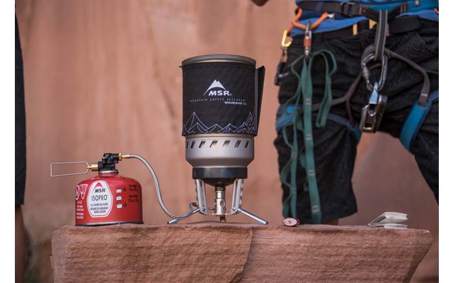 Fornellino da campo su una lastra di roccia accanto a una bomboletta di gas e attrezzatura da arrampicata