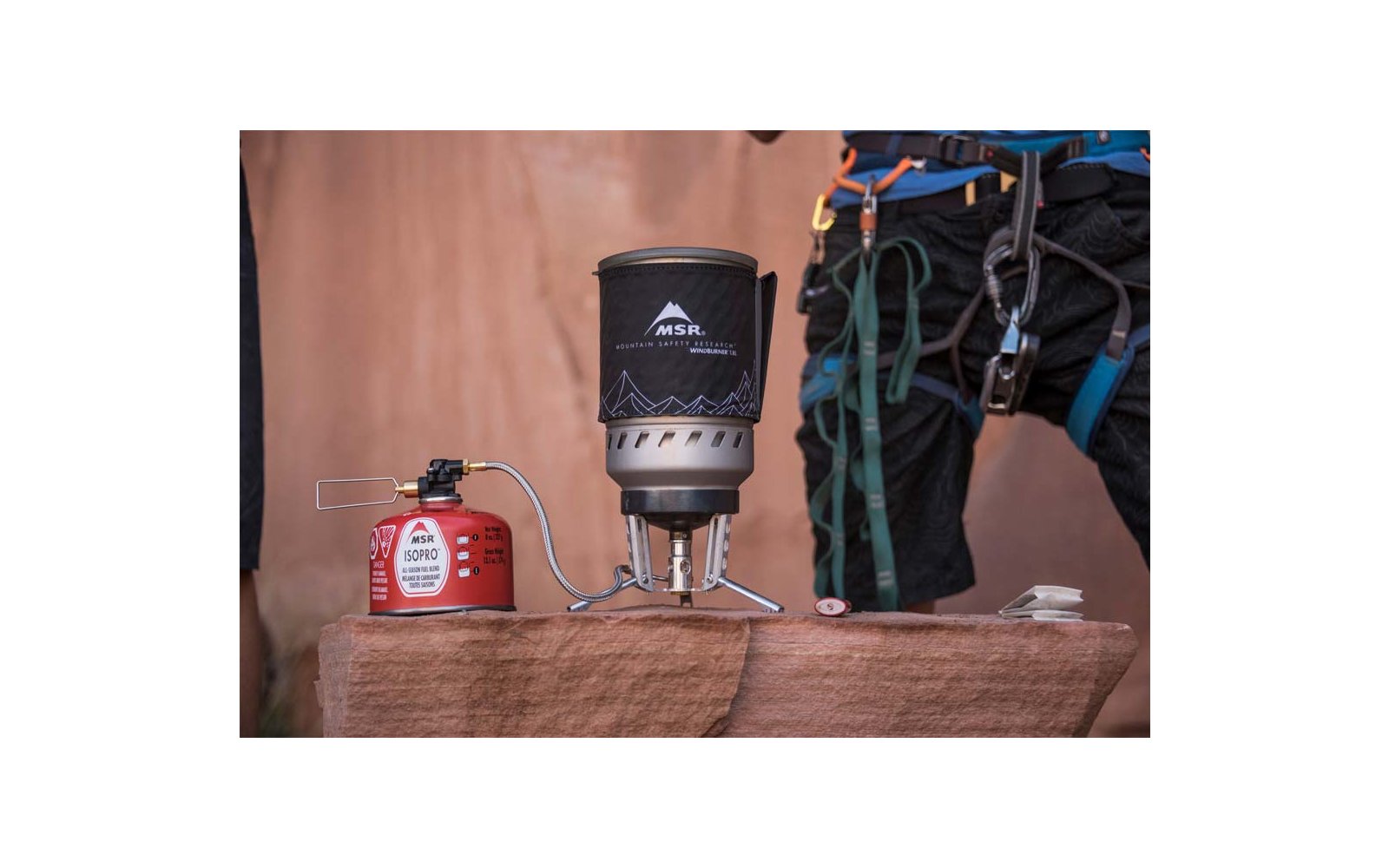 Fornellino da campo su una lastra di roccia accanto a una bomboletta di gas e attrezzatura da arrampicata