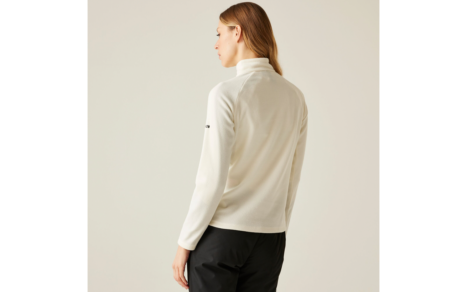 Frau mit roten Haaren, die einen hellen Pullover und schwarze Hose trägt, von hinten fotografiert