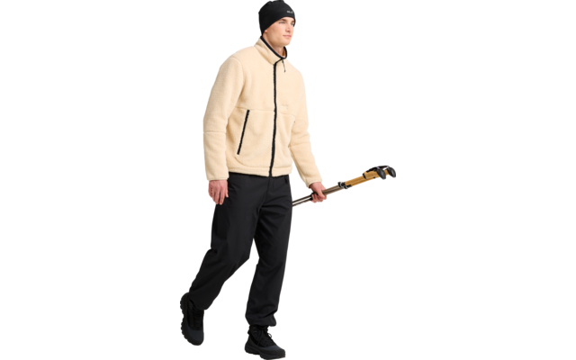 Person in beige Fleecejacke, schwarzer Mütze und schwarzer Hose, hält ein langes Werkzeug mit gelbem Griff