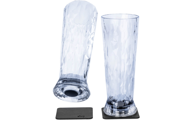 Two tall clear glasses with a faceted pattern; one stands on a dark square coaster, the other lies on its side on a second coaster