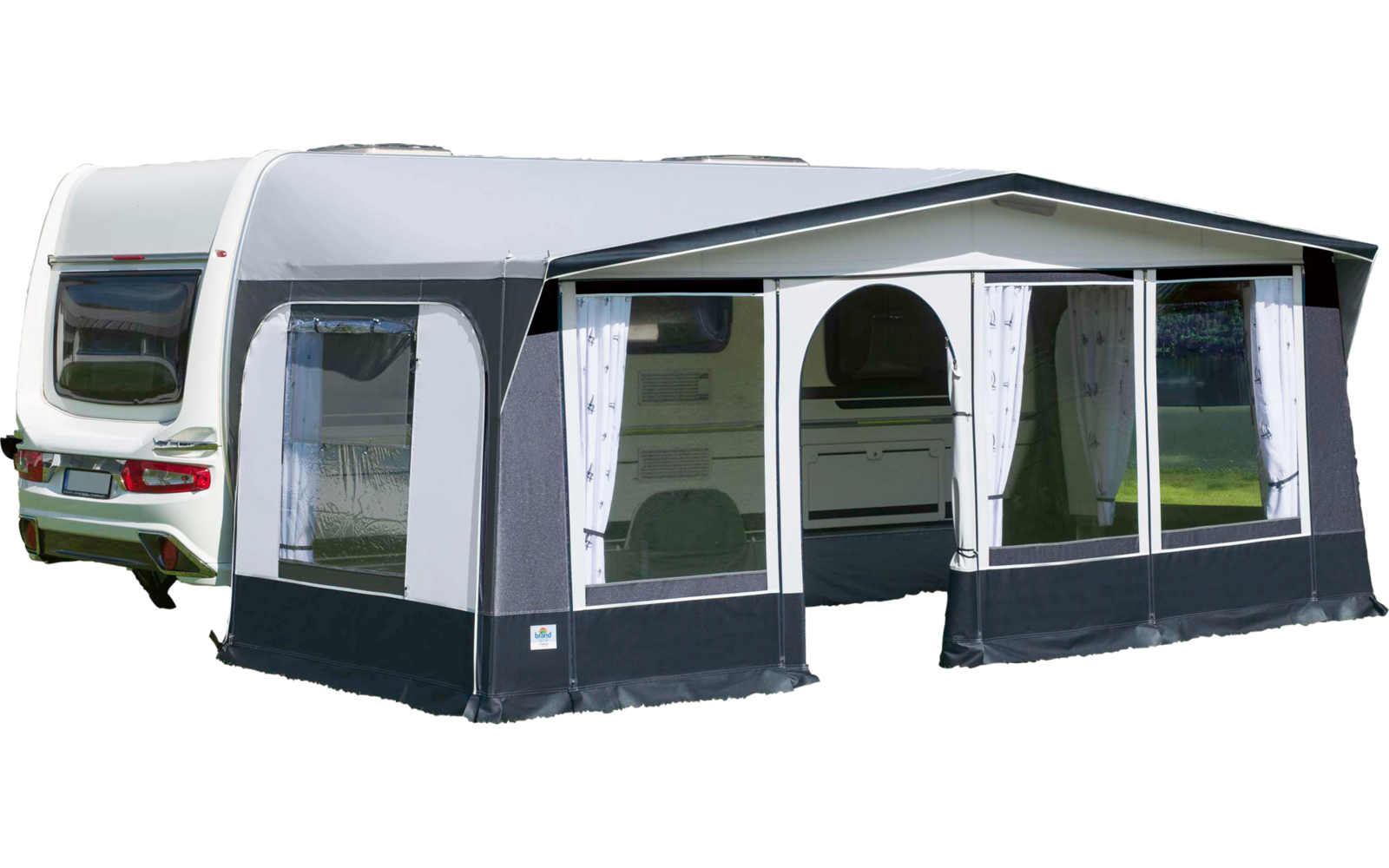 Weißer Wohnwagen mit angebautem Vorzelt auf grüner Wiese an einem See, Berge im Hintergrund