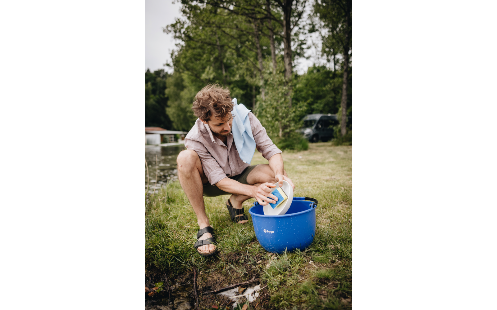 Persoon die buiten zit en hun voeten wast in een blauwe emmer met water