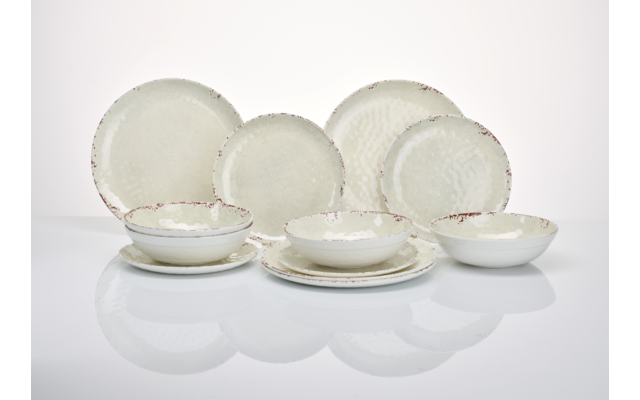 Mehrere cremefarbene Keramikteller und -schalen mit unregelmäßig braunem Rand auf weißer Fläche