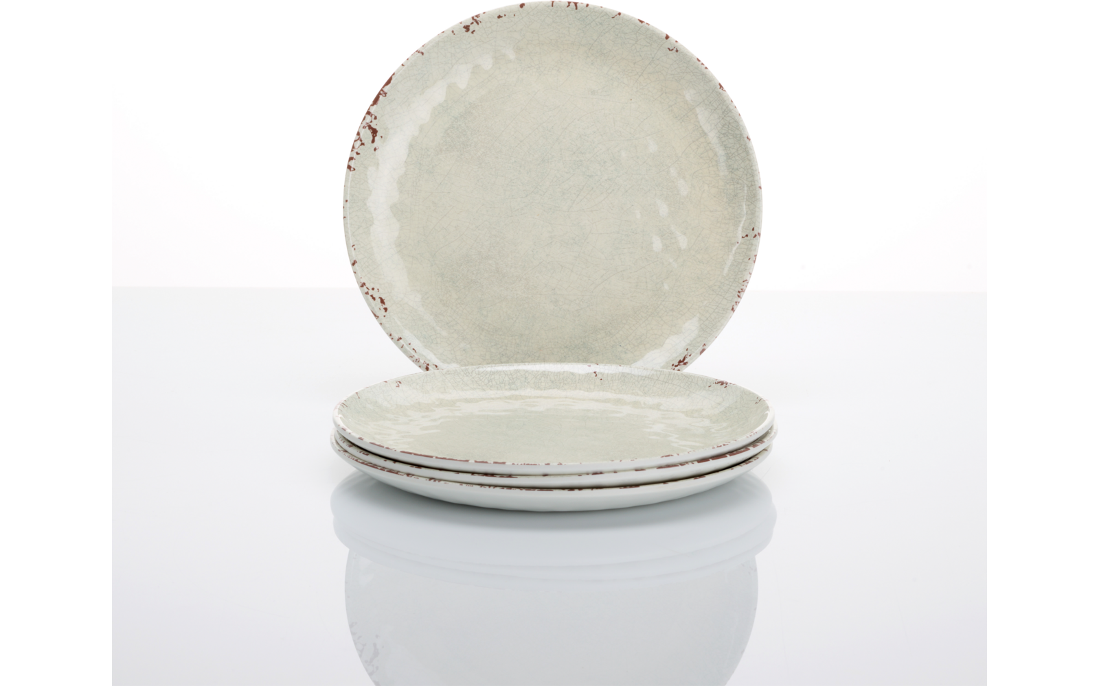 Drei hellgraue Keramikteller, zwei gestapelt vorne, einer steht dahinter auf weißem reflektierendem Untergrund