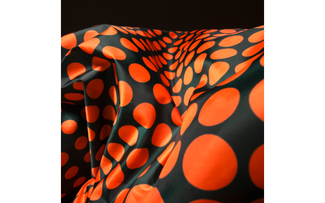 Black fabric with large orange polka dots and folds