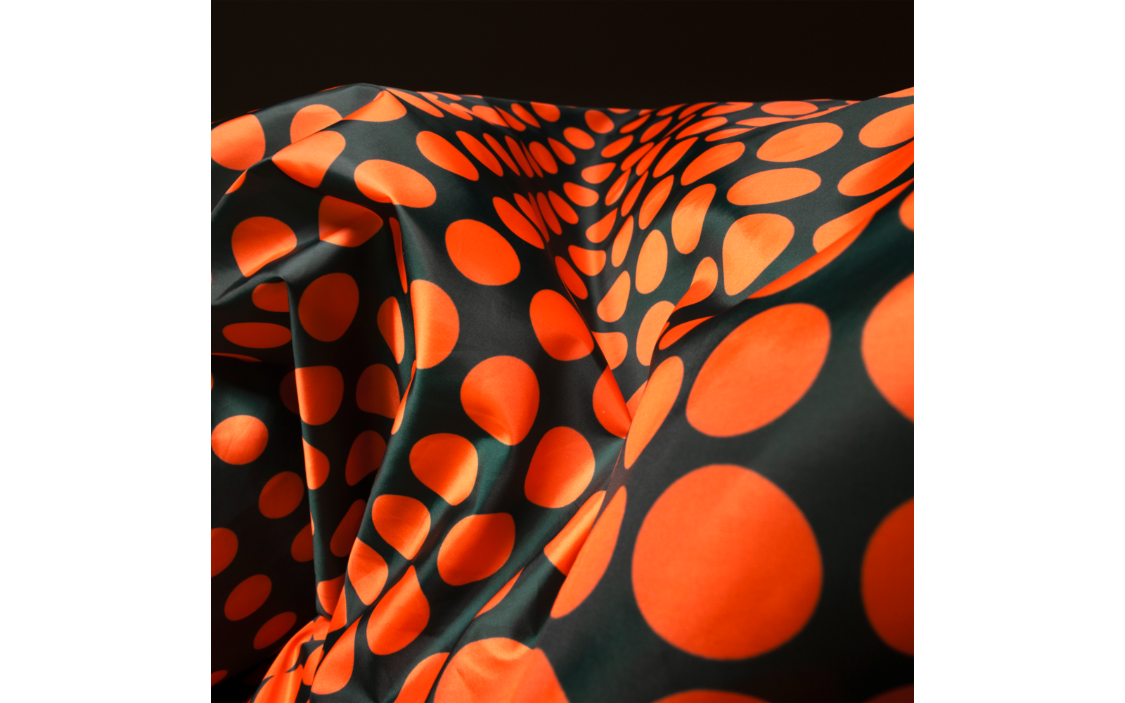 Black fabric with large orange polka dots and folds