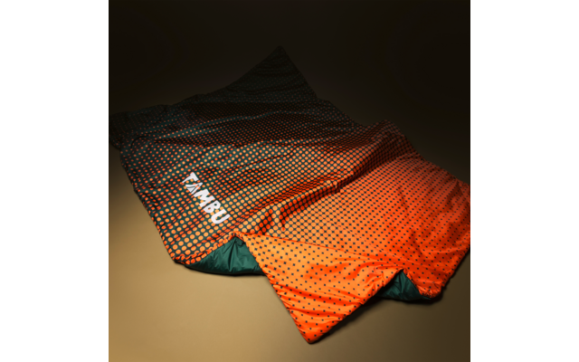 Spread-out orange sleeping bag with black dots, green inner lining and white brand text "TAMBU" on a beige background