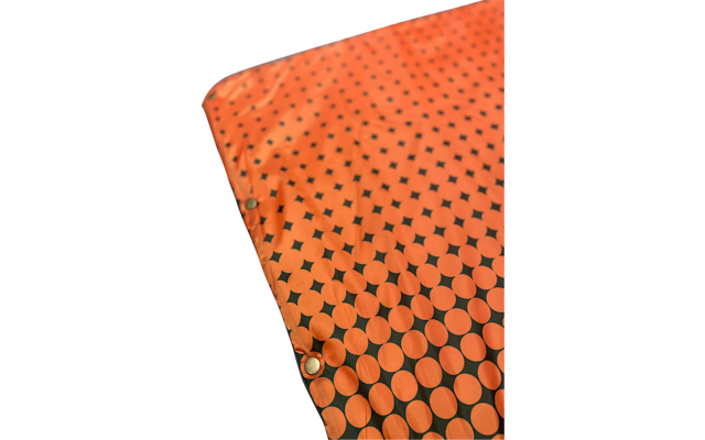 Orange fabric with black circular and diamond-shaped pattern and metal grommets along the edge