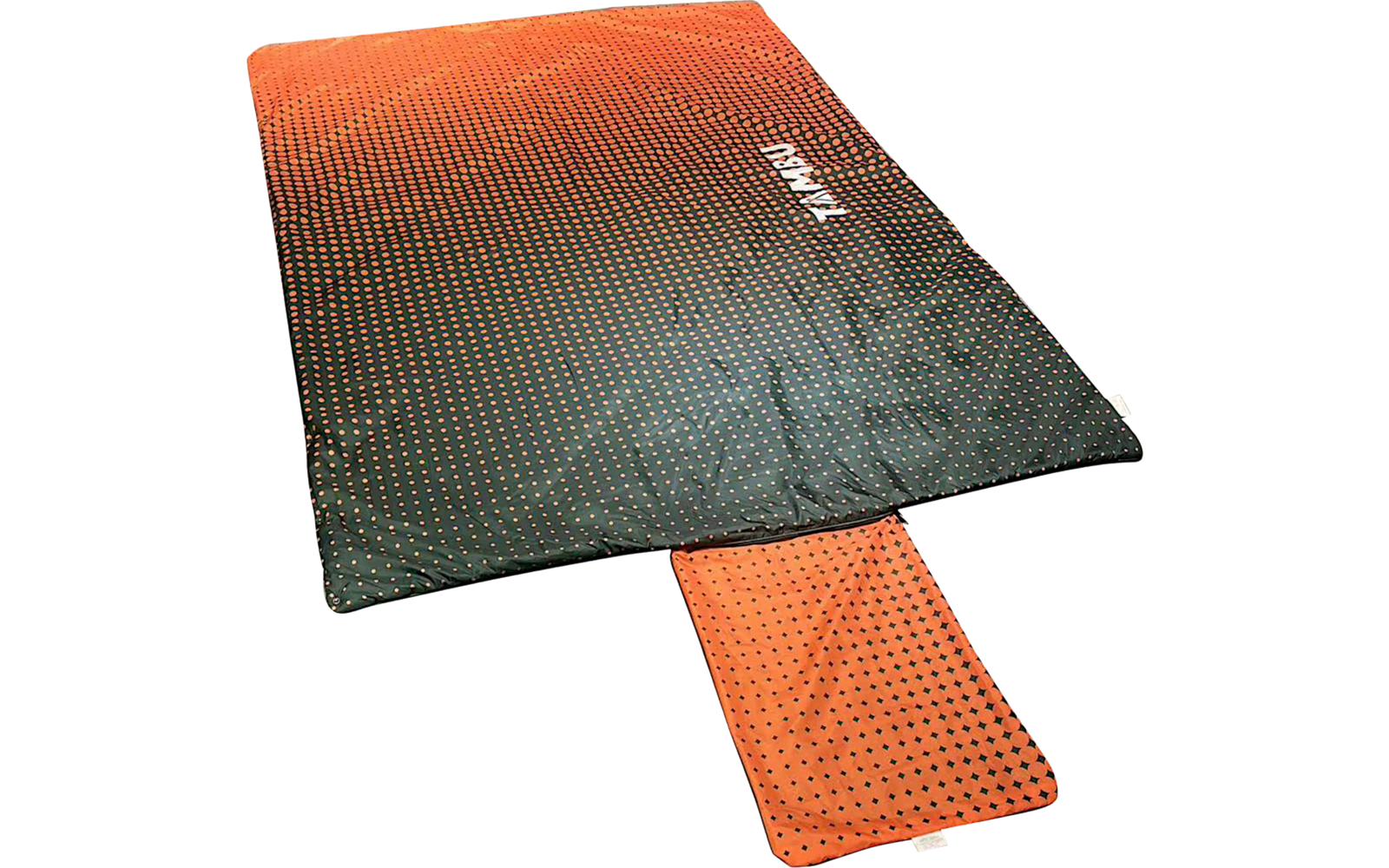 Rectangular two-tone textile (orange to dark green) with small dots; a narrow orange rectangle extends out; white text "NOMAD"