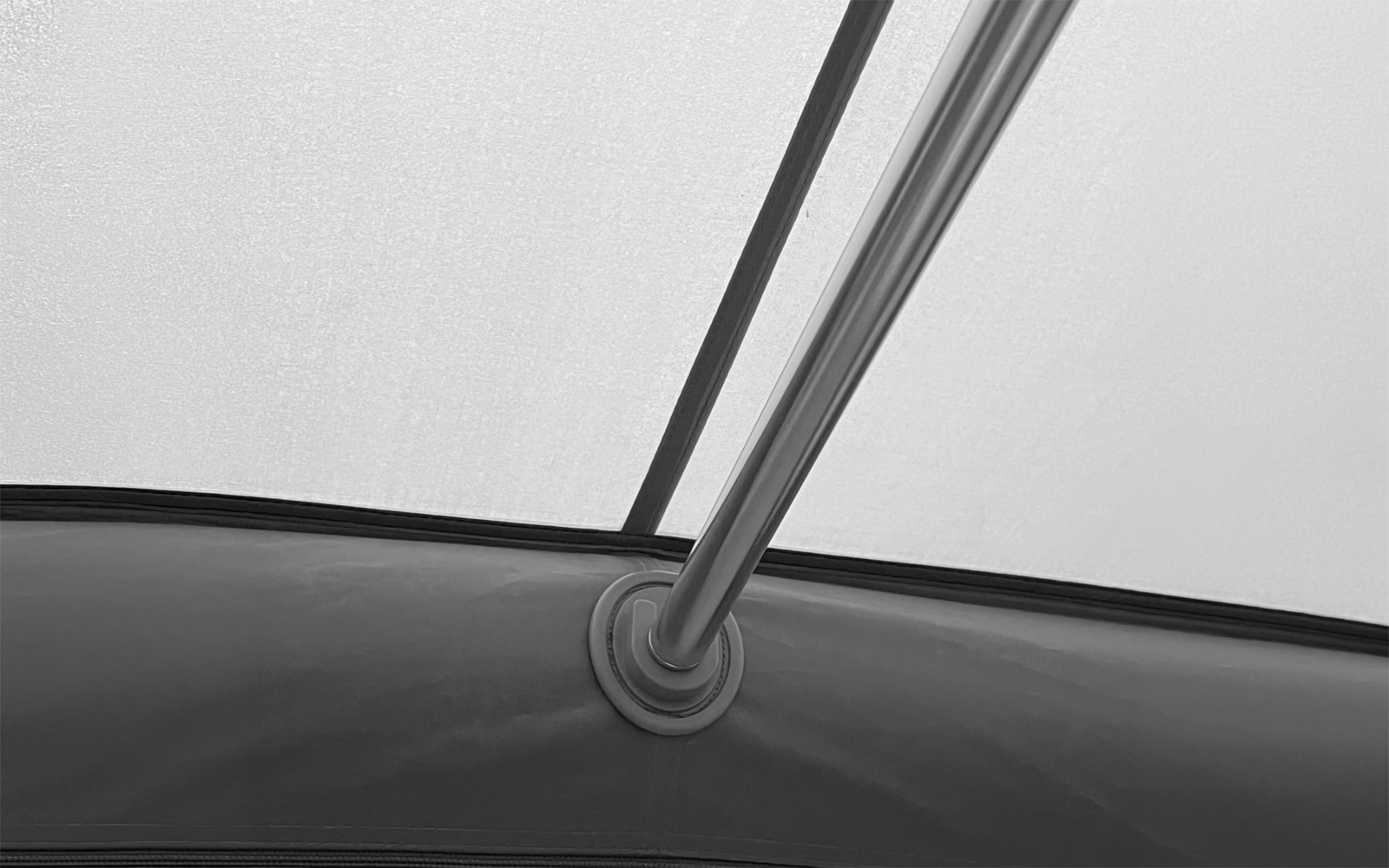 Intérieur d’un tissu clair avec une tige métallique verticale fixée par un anneau en plastique circulaire au bord du tissu
