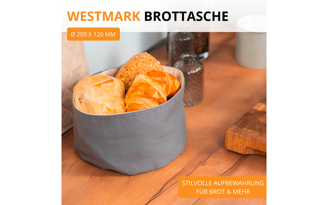 Sac à pain en tissu gris avec petits pains et croissant sur une table en bois; salière et poivrière, tasse blanche et planche en bois en arrière‑plan; texte 'WESTMARK BROTTASCHE', indication 'Ø 200 x 120 MM' et étiquette orange 'STILVOLLE AUFBEWAHRUNG FÜR BROT & MEHR'