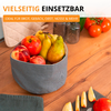 Panier en tissu avec pommes, poires et bananes sur une table en bois ; quartiers de pomme tranchés sur une planche, tomates, deux vases en verre et un textile matelassé en arrière-plan. Texte visible en haut : "VIELSEITIG EINSETZBAR" et "IDEAL FÜR BROT, GEBÄCK, OBST, NÜSSE & MEHR"