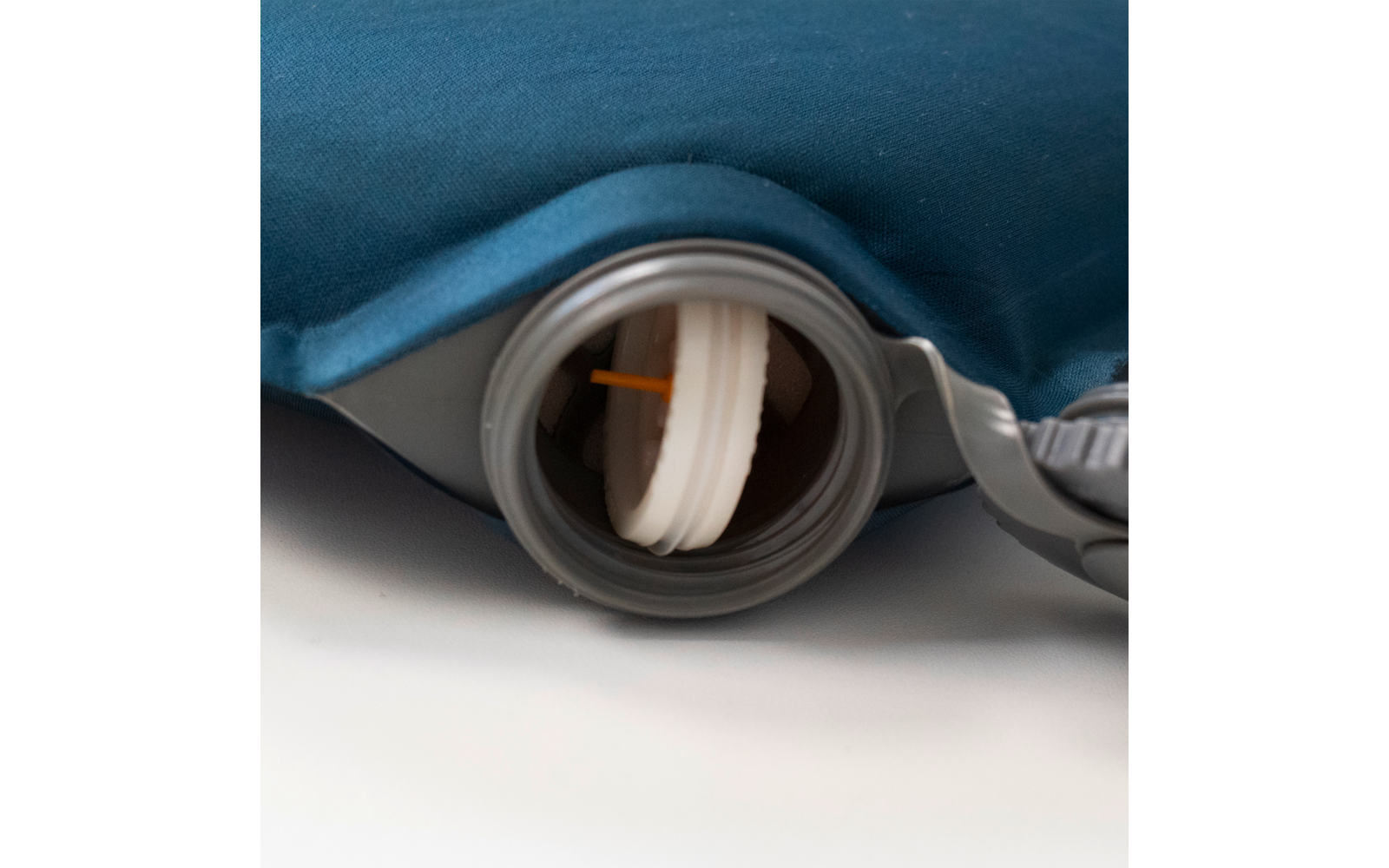 Nahaufnahme eines geöffneten grauen Kunststoff-Schraubverschlusses an einem blau bezogenen Behälter, sichtbar ein weißer Stopfen mit orangefarbenem Ziehband