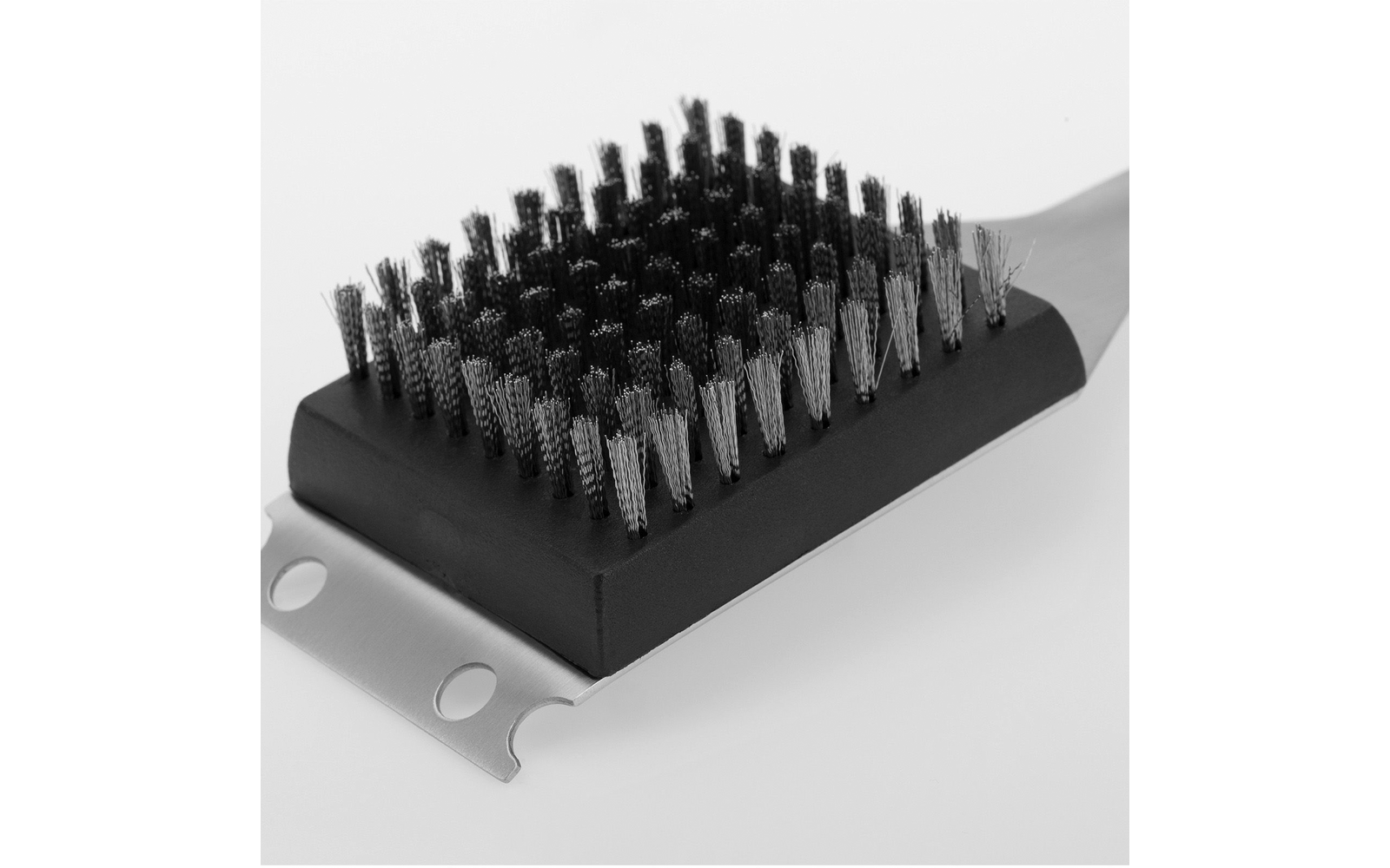 Brosse rectangulaire avec poils métalliques denses sur un socle en plastique noir ; pièce métallique plate fixée avec deux trous ronds et un bord entaillé
