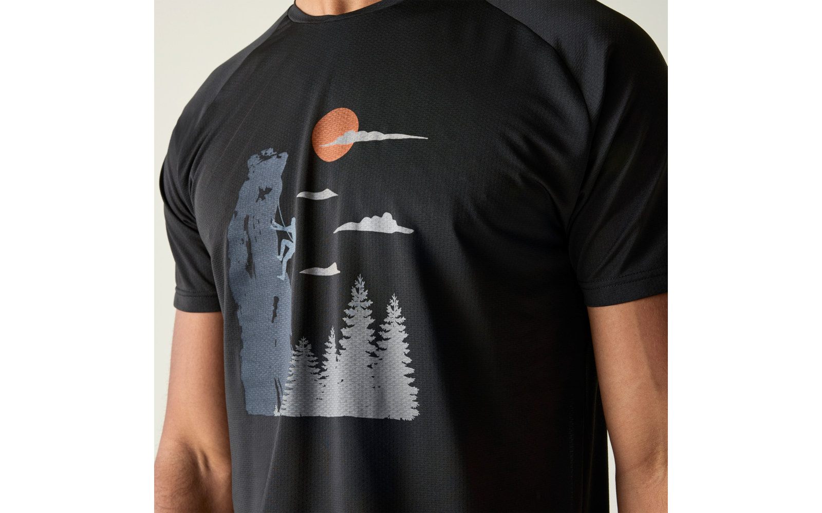 Oberkörper in schwarzem T‑Shirt mit Aufdruck: Kletterer an Felswand, Tannen, Wolken und orange Sonne