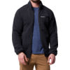Mann trägt schwarzen Fleecepullover über blauem T-Shirt und beigen Hosen