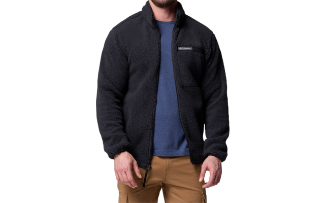 Mann trägt schwarzen Fleecepullover über blauem T-Shirt und beigen Hosen