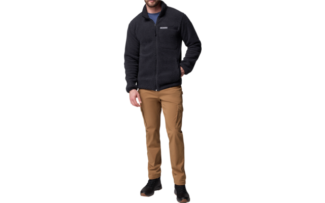 Mann trägt schwarze Jacke, braune Hose und schwarze Schuhe, steht vor weißem Hintergrund