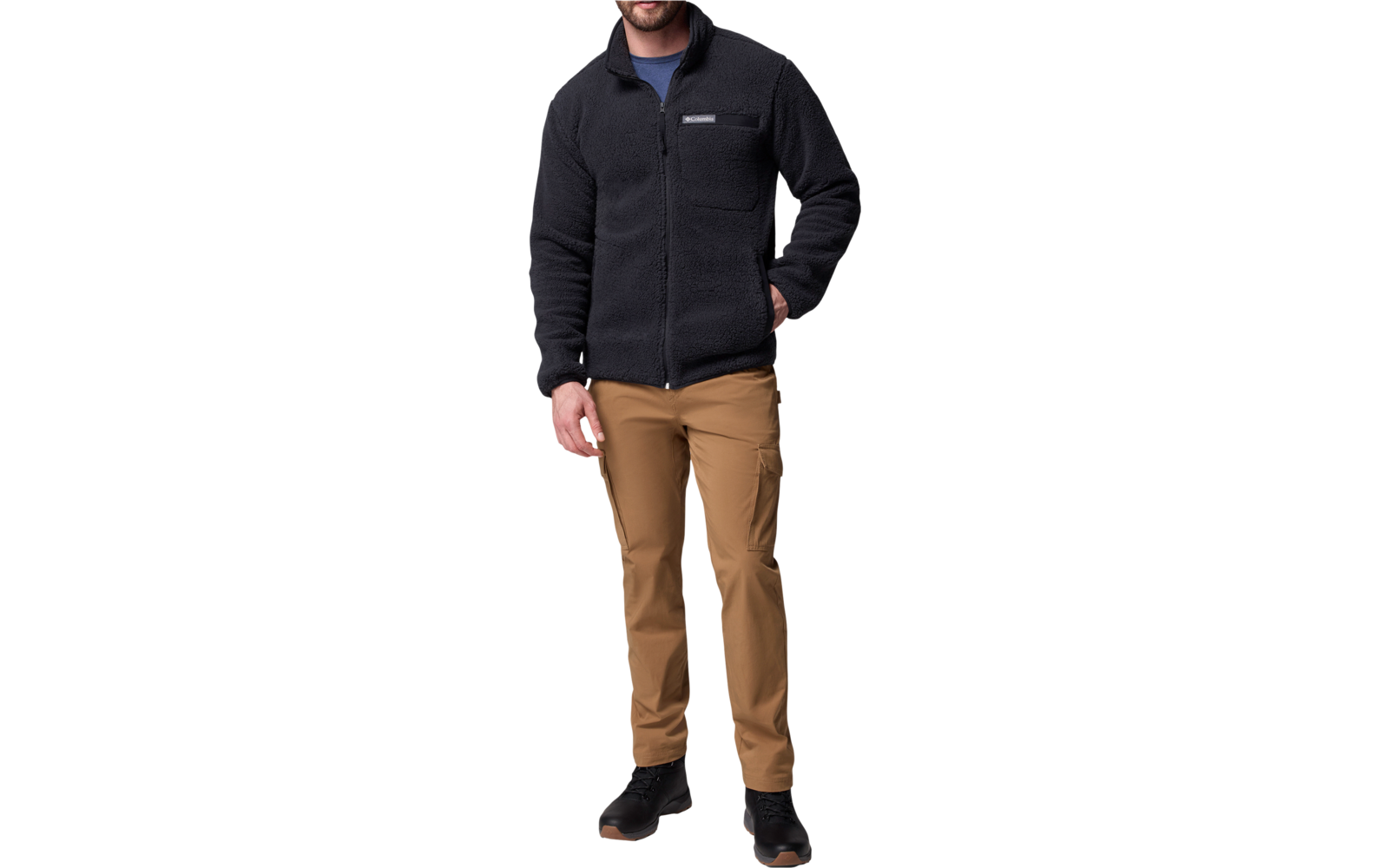 Mann trägt schwarze Jacke, braune Hose und schwarze Schuhe, steht vor weißem Hintergrund